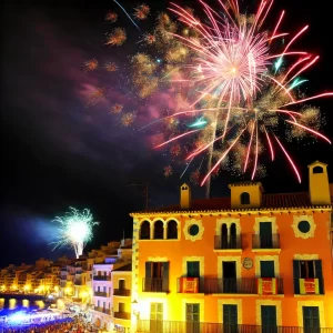 Een levendige vuurwerkshow boven een Spaanse stad met kleurrijke lichten die de iconische gebouwen met terracotta daken en balkons verlichten, terwijl mensen naar de feestelijkheden kijken. vuurwerk in spanje is populair